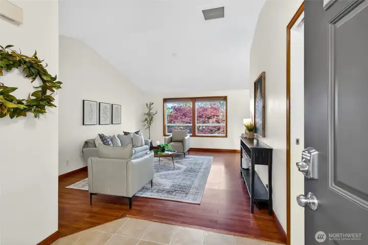 Living room with vaulted ceilings and views of the tree line gives it a private and open feel.