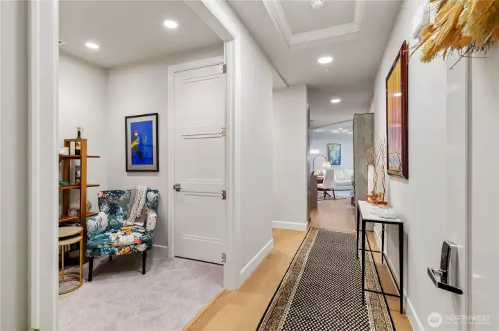 Welcome home to a wide, gallery-style entryway with rich hardwood floors and elegant tray ceilings—Just off the entry, a versatile flex room offers the perfect spot for a stylish home office, cozy guest space, or reading nook, complete with plush carpeting and privacy (The current owner removed the original doors to create an open, welcoming feel, but they can easily be reinstalled to convert the space back into a private den or guest room).