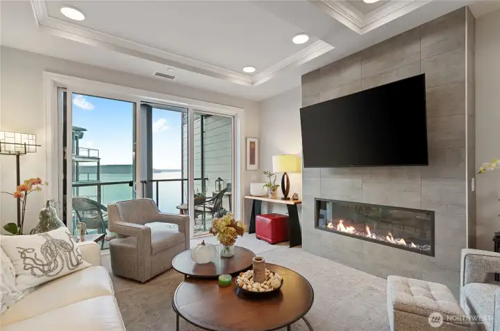 Contemporary living room dedicated space, cozy electric fireplace, oversized sliders – perfect Puget Sound views open to a private balcony for seamless indoor-outdoor living and entertaining.