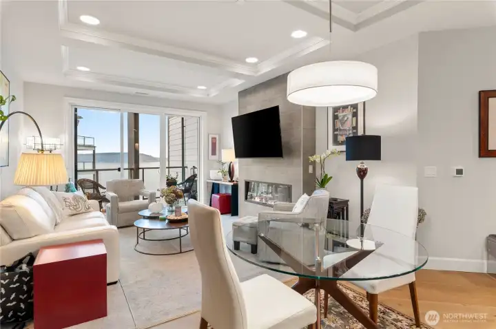 Step into elegance—this light-filled great room stuns with dramatic tray ceilings, customizable recessed lighting, and a sleek electric fireplace for cozy evenings.