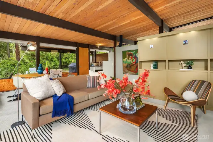 Surrounded by windows, a door between dining and kitchen opens to a west-facing covered patio and deck.
