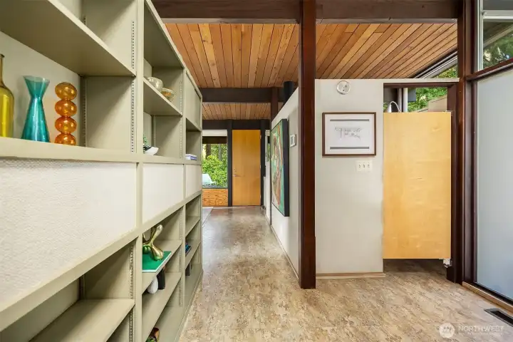 The front door is just to our right, out of frame.  Kitchen is straight ahead through the saloon door.  On our left is the other side of the living room built-in shelving.