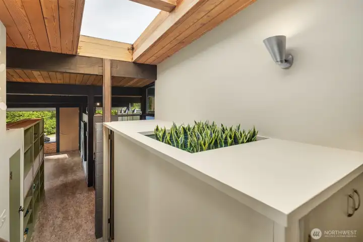 We've got faux plants here, but that's a real, functional planter with external drainage and everything!  A large skylight graces the upper bedrooms, landing, and main entry with natural light.  The door to the 2-car attached garage is just to our right.