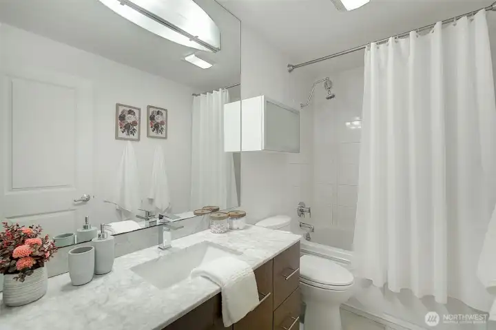 A light and bright bathroom with gorgeous countertops and tiled shower surround.