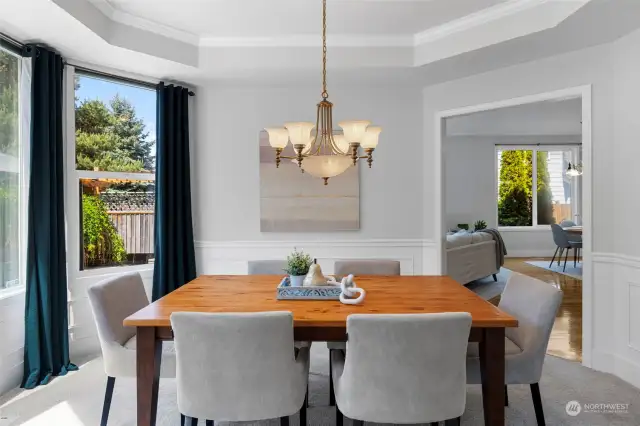 Formal dining room with recessed ceiling and wainscoting details.
