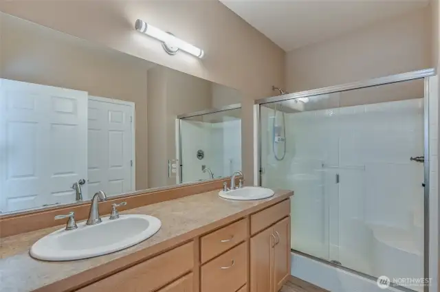 The primary bathroom has a dual sink vanity, step-in shower and private water closet with storage.