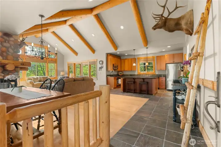 Vaulted great room with exposed beams, stone fireplace, and open layout.