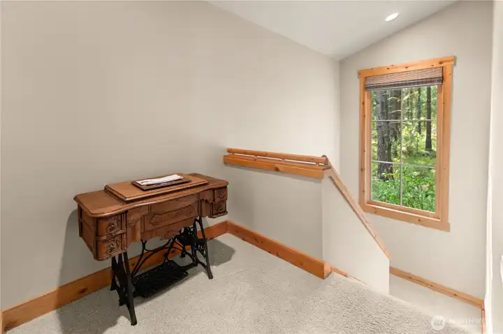 Sunny landing at the top of the stairs – ideal spot for a cozy reading nook or small home office with forested views.