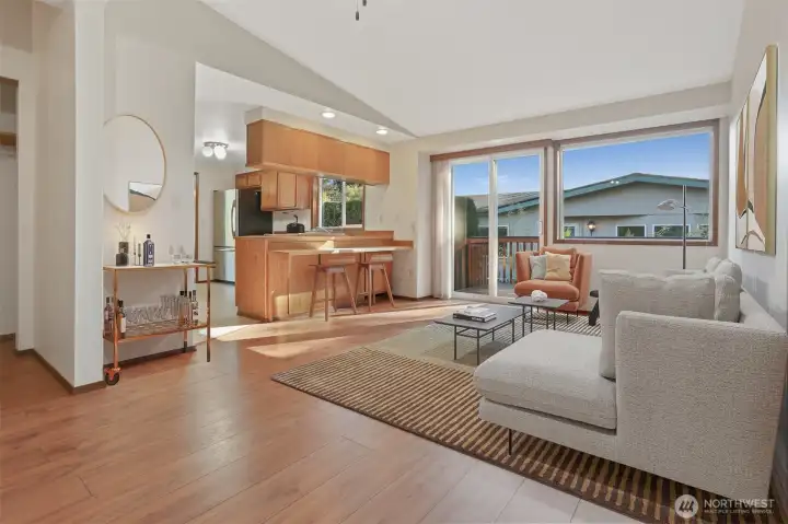 Family room with laminate hardwoods opens to kitchen with an eating bar and has sliding door to south facing deck.  Virtually staged photo.