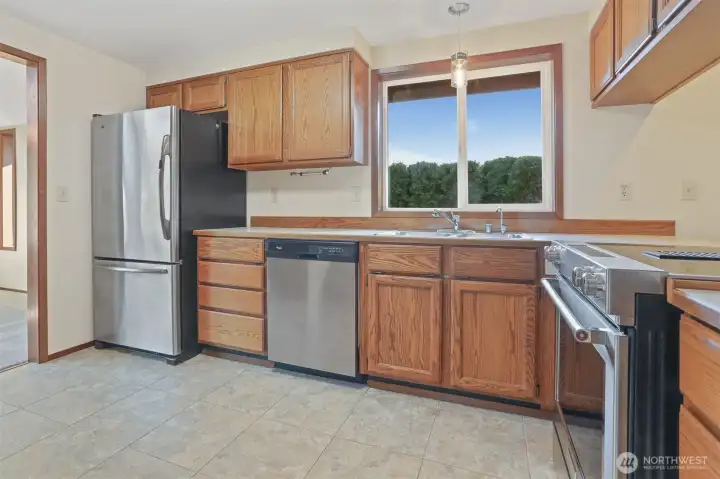 Kitchen features oak cabinets, stainless appliances including a newer kitchen aide downdraft range, an eating bar and opens to family room.