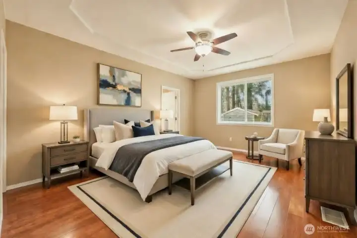 Designed as a private sanctuary, the primary suite features a sophisticated tray ceiling, gleaming floors, and abundant natural light. The spacious layout easily accommodates a sitting area, creating a tranquil retreat that blends comfort, elegance, and everyday livability. A ceiling fan and central air conditioning ensure comfort in every season.