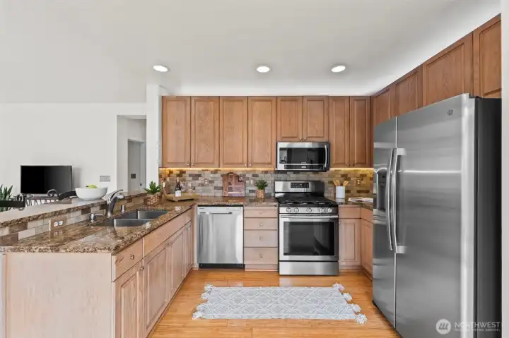 Chef’s Delight. This well-appointed kitchen features classic wood cabinetry, sleek granite countertops, and a full suite of stainless steel appliances. The tile backsplash and under-cabinet lighting add a touch of luxury to this highly functional workspace.