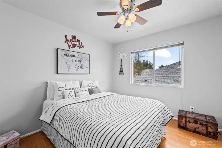 Charming & Bright. This well-proportioned secondary bedroom is filled with personality and natural light. With beautiful hardwood-style floors and a modern ceiling fan, it serves as a comfortable guest room, nursery, or creative space.