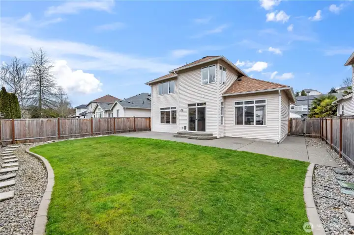 Private Outdoor Oasis. The lush green lawn is fully enclosed by a privacy fence, offering a safe and serene space for play or relaxation. Professional landscaping and stone pathways add an extra touch of charm.