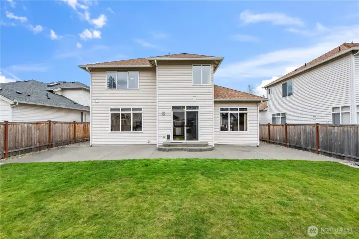 Immaculate Design. This view of the rear of the home highlights the large windows and modern siding. The spacious patio and manicured lawn create the ultimate backyard retreat for any homeowner.