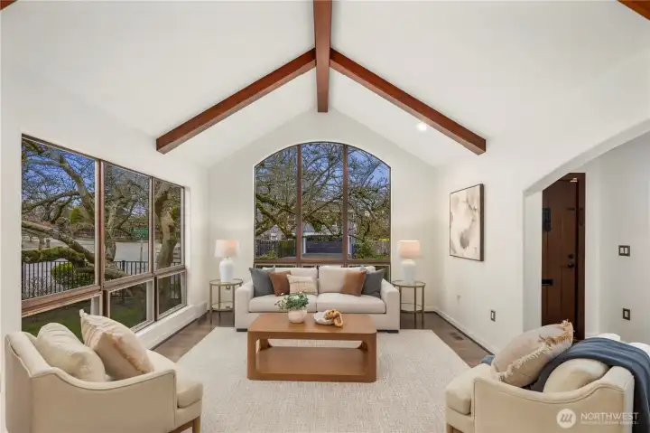 The living room impresses with soaring vaulted ceilings, exposed wood beams, and expansive picture windows that fill the space with natural light.