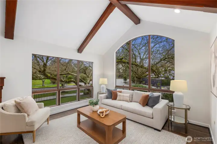 The living room impresses with soaring vaulted ceilings, exposed wood beams, and expansive picture windows that fill the space with natural light.