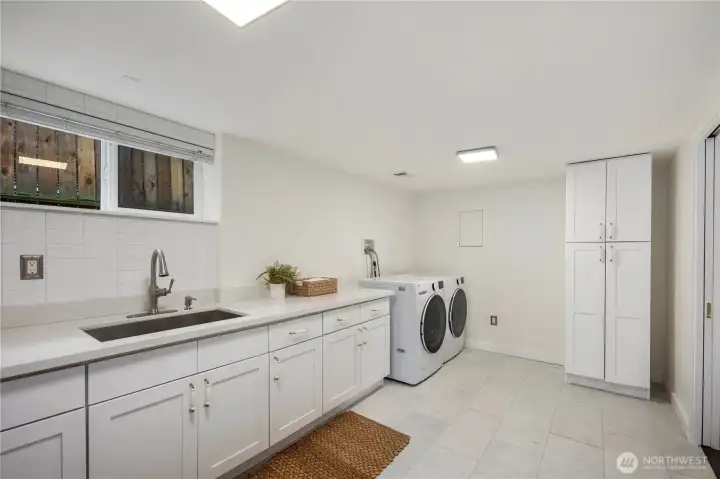 Large laundry room featuring a generous folding counter and utility sink, making everyday tasks both functional and efficient.