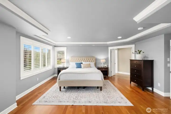 Generously sized primary bedroom with hardwood floors, plantation shutters, cove molding and Mt. Rainier views!