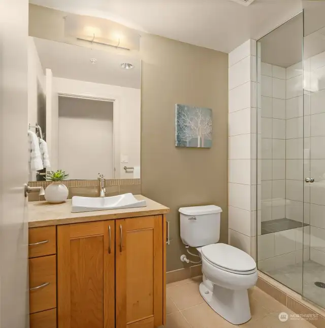 Bright three quarter guest bath just off the entry hallway includes a tile shower with a bench.