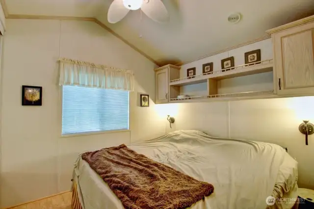 Bedroom with ceiling fan and storage by bed