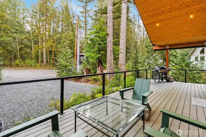 Covered deck seating area overlooking peaceful forest surroundings.
