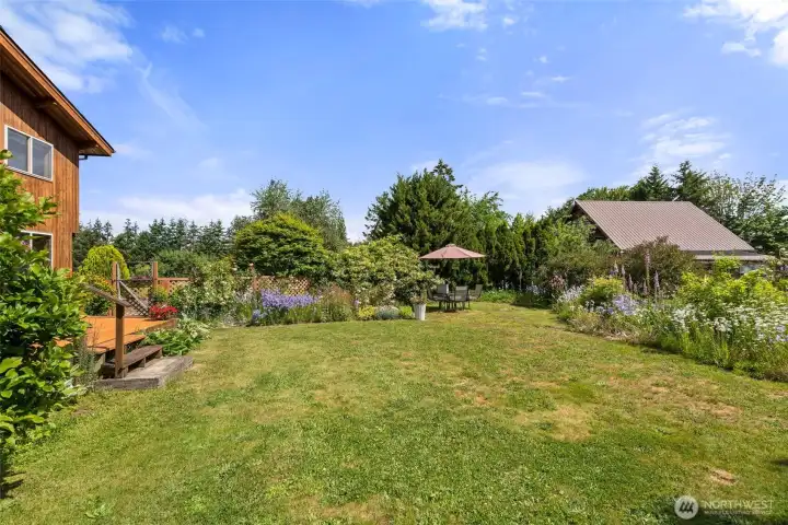 Yard and flower beds on east side of house. Deck on left leads into dining room. Yard and flower beds on east side of house. Deck on left leads into dining room.