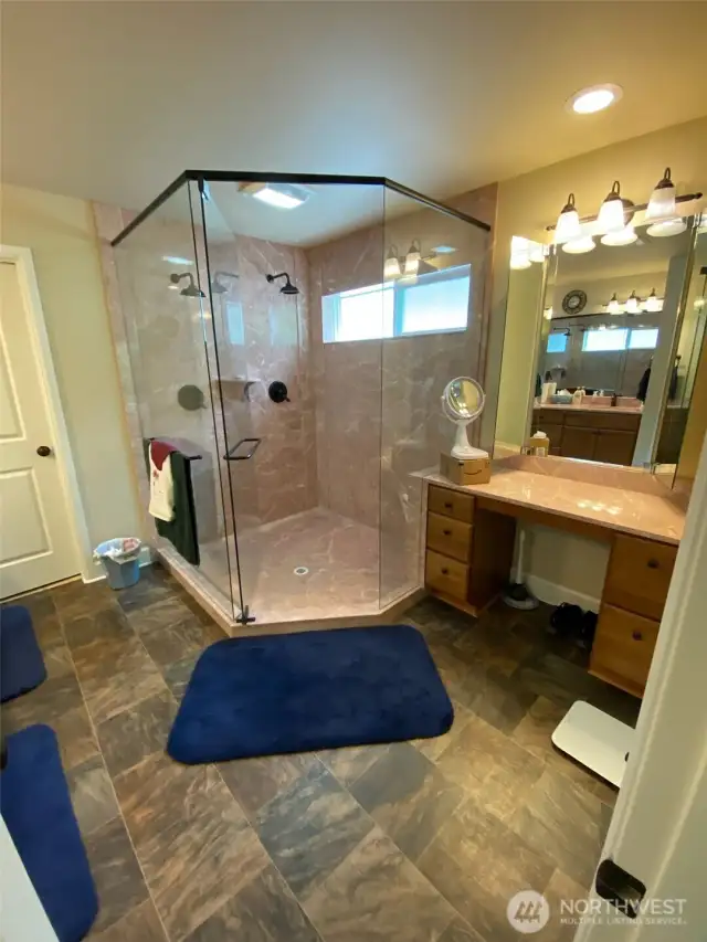Photo taken by Seller prior to Tenant Occupancy. Remodeled primary bath has expanded shower with 2 shower heads and seated make up vanity