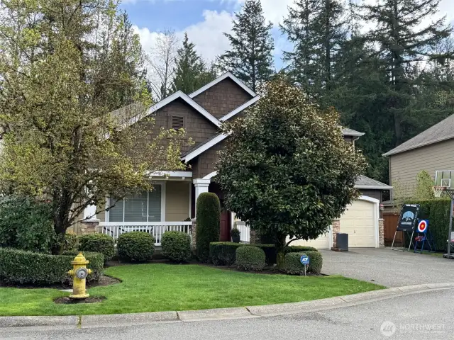 Mature trees and flowering shrubs grace the front yard