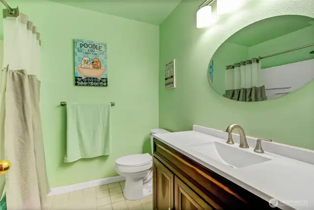 Main hallway bathroom, conveniently near bedrooms and ideal for guests, features a combo tub/shower, updated vanity, sink, toilet, and tile flooring.
