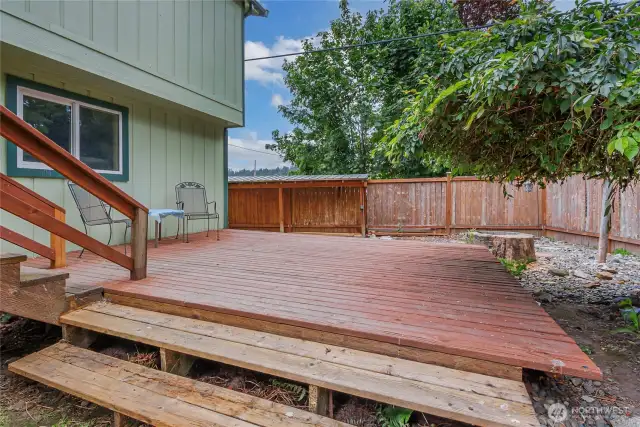 Lower deck steps down to a beautifully landscaped backyard with a separate fire pit area and a wood shed nearby—perfect for cozy evenings and outdoor entertaining.