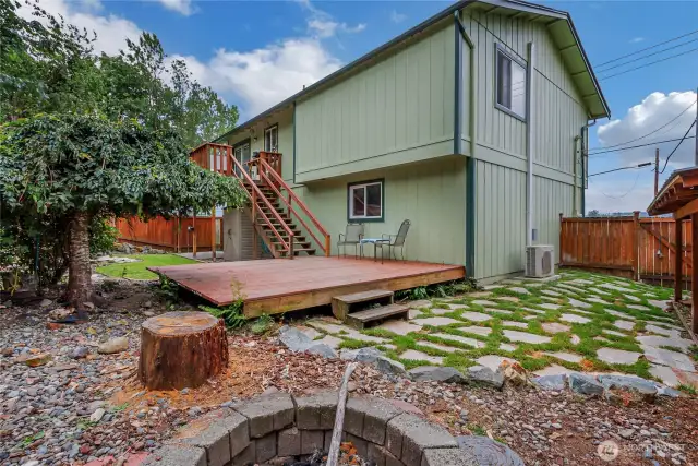 The lower deck opens to a side yard with paver walkway and a cozy fire-pit area—ideal for entertaining and relaxing outdoors.
