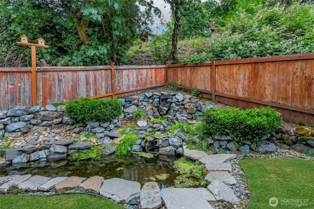 Tranquil backyard oasis featuring a serene water feature with pond and gentle waterfall.