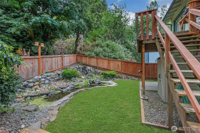 Enjoy the soothing sounds of a cascading waterfall in this fully fenced, beautifully landscaped backyard. The natural stone pond and greenery create a calming outdoor space ideal for unwinding or entertaining.