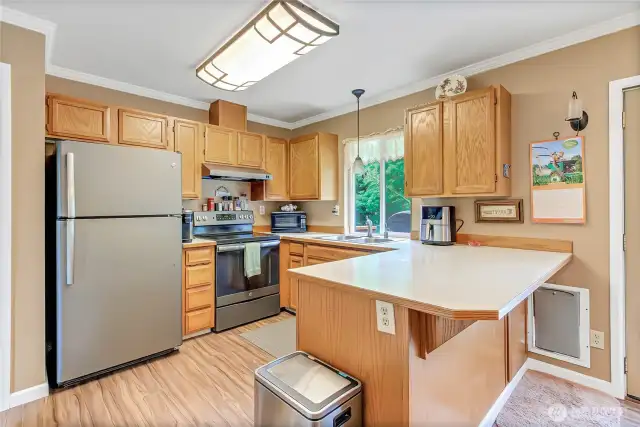 Conveniently located kitchen features an eating bar, stylish appliances, pantry, and a window above the sink overlooking the gorgeous backyard—seamlessly open to the dining and living room for effortless entertaining.