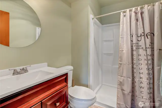Updated primary bathroom with tile flooring, conveniently located off the primary bedroom, featuring a shower, sink, and toilet.