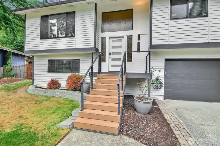 Fresh exterior paint, new front door, and welcoming porch with modern railing.