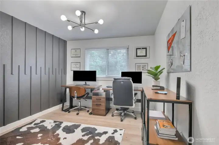 2nd bedroom or office with trendy wall, new flooring, and lighting.