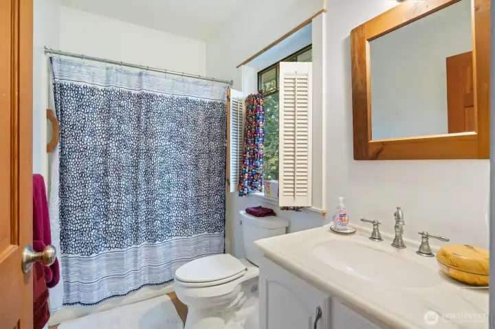 Second bedroom bathroom with bathtub/shower and charming shutter details