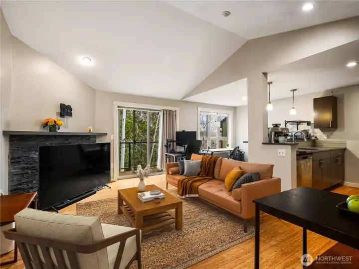 Tall vaulted ceilings make the space feel roomy and airy. (virtually staged except for large tv infront of fireplace)