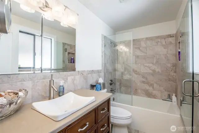 Secondary/guest bathroom on main floor beautifully updated with quartz countertops, tile floors and shower walls