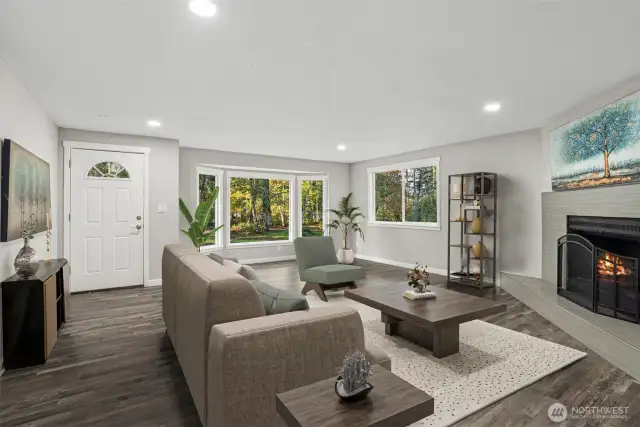 The home features expansive glass windows and doors, allowing an abundance of natural light to fill the space, even with trees on the property. The trees are set at a perfect distance—not too close to obstruct the view yet providing ample shade during sunny summers. Their beauty adds to the charm of the surroundings. The fireplace imparts a sense of coziness, warmth, and positive energy. The open, airy, and easy flow of this family room is ideal for both daily living and entertainment. Canned lighting adds bright, non-glaring light, enhancing the overall ambiance. Luxury Vinyl Plank flooring adds beauty.