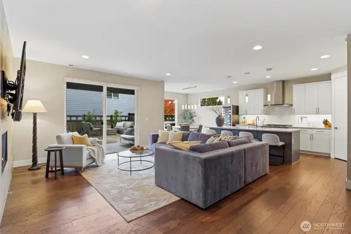 Large great room with high ceilings and grand chef's kitchen. Gas Fireplace, custom mounted TV, floor to ceiling tile surround.