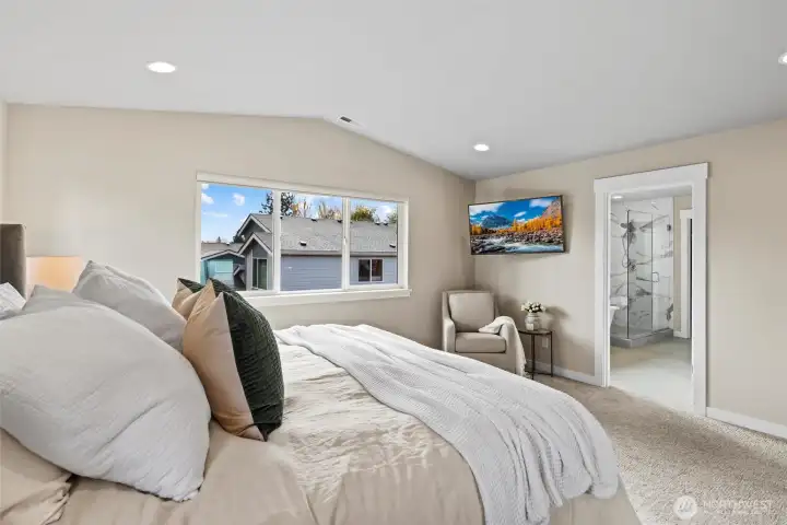 Primary Bedroom with spa inspired ensuite bath and vaulted ceilings. Remote operated blinds and custom mounted TV.