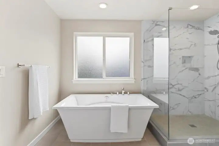 Spa inspired primary bath with large shower, soaking tub, and grand walk-in closet.