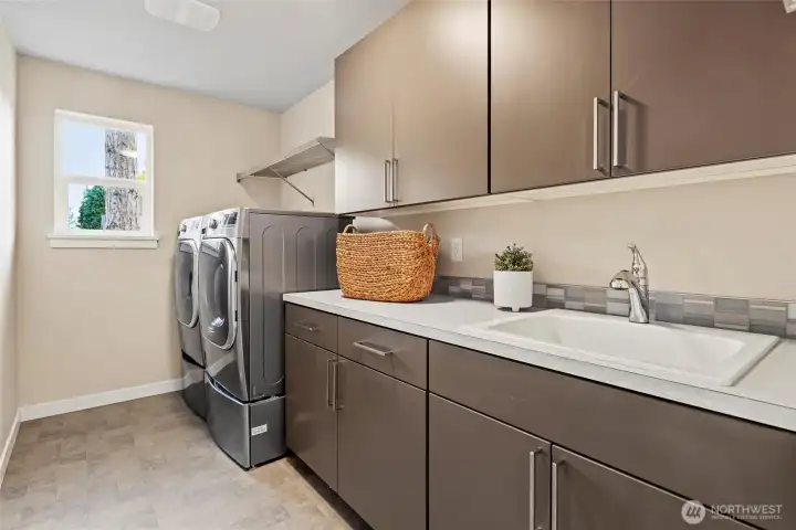 Upstairs laundry room with utility sink and LG TrueSteam pedestal washer/dryer