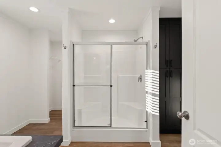Bright primary bedroom private bath featuring double vanity, large shower, extra cabinetry for storage and big walk-in closet