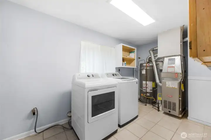 This spacious utility room offers ultimate convenience, doubling as a walk-in pantry with plenty of extra storage potential. Features include a modern washer and dryer set, and easy access to the home's updated mechanical systems.