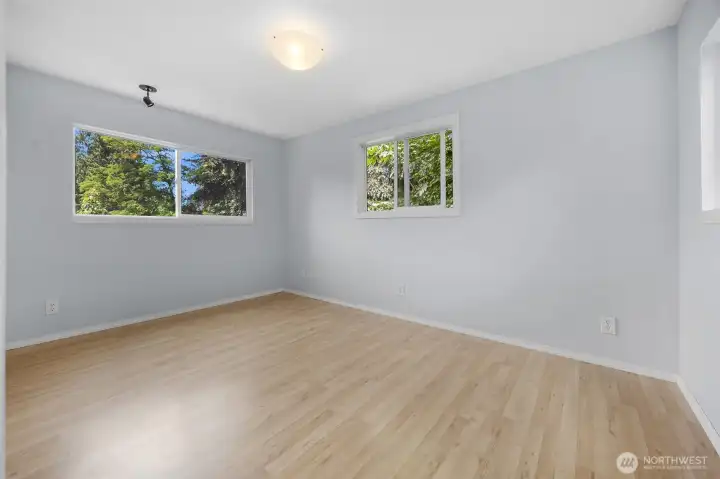Fantastic upper-level fourth bedroom! This generous room boasts clean, light-colored laminate flooring, fresh neutral paint, and multiple windows filling the space with plenty of natural light.