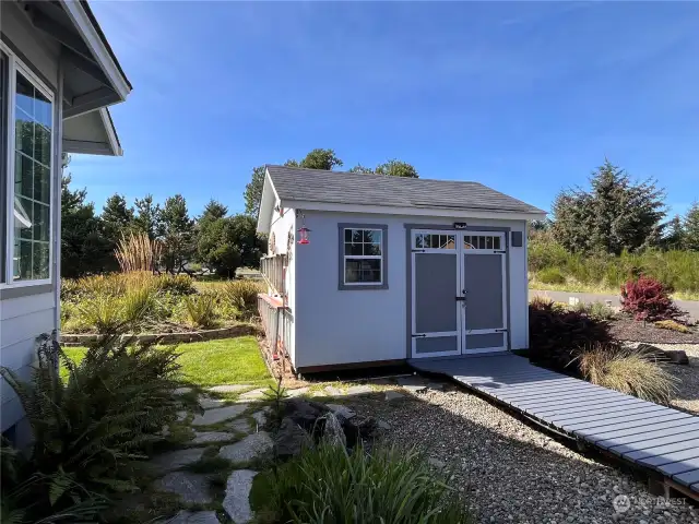 Shed with wooden walkway to hold water toys and lawn equipment by the front of the home